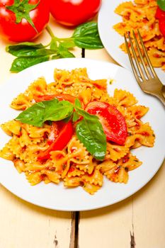 Italian pasta farfalle butterfly bow-tie with tomato basil sauce over white rustic wood table