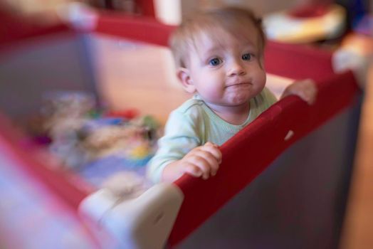 cute  little baby playing with toys in mobile bed making first steps and learnig to stand  and walk