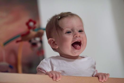 cute  little one year old baby playing with toys in bed while making first steps and learnig to walk