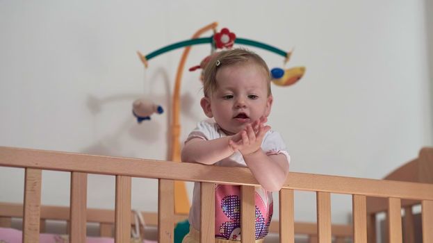 cute  little one year old baby playing with toys in bed while making first steps and learnig to walk