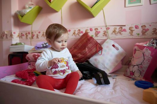 cute  little one year old baby playing  with toys at home while making first steps and learnig to walk