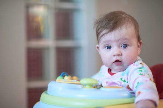 cute little baby learning to walk in walker at home