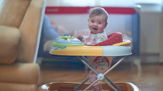 cute little baby learning to walk in walker at home