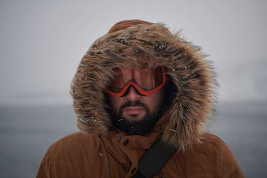 portrait local authentic eskimo  man at winter in stormy weather wearing warm  fur jacket