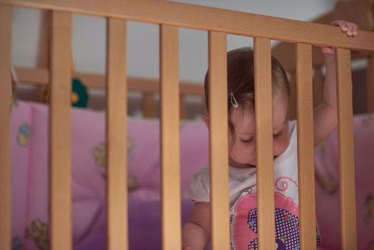 cute  little one year old baby playing with toys in bed while making first steps and learnig to walk