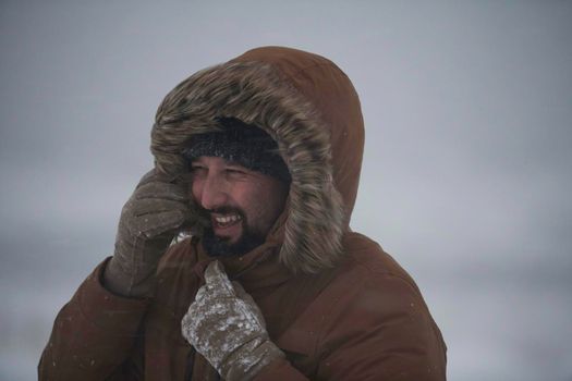 portrait local authentic eskimo  man at winter in stormy weather wearing warm  fur jacket