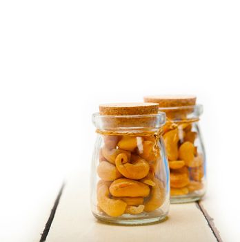 cashew nuts on a glass jar over white rustic wood table 