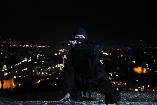 ninja assasin hold katana samurai old martial weapon swordat night with city lights in background