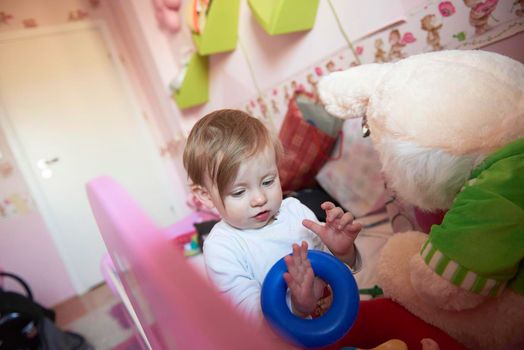 cute  little one year old baby playing  with toys at home while making first steps and learnig to walk