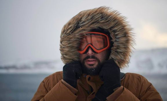 portrait local authentic eskimo  man at winter in stormy weather wearing warm  fur jacket