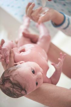 Mother is bathing Newborn baby girl taking a bath