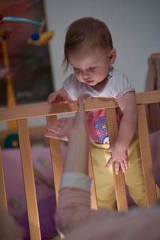 cute  little one year old baby playing with toys in bed while making first steps and learnig to walk