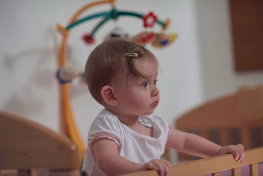 cute  little one year old baby playing with toys in bed while making first steps and learnig to walk