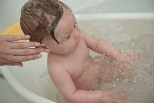 Mother is bathing happy little  baby girl taking a bath