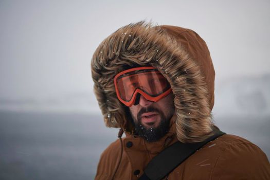 portrait local authentic eskimo  man at winter in stormy weather wearing warm  fur jacket