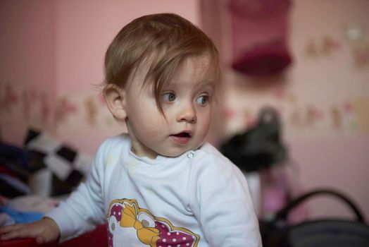 cute  little one year old baby playing  with toys at home while making first steps and learnig to walk