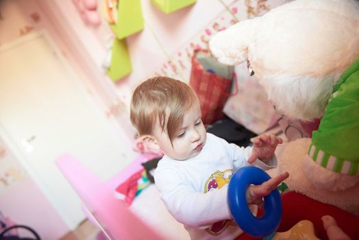 cute  little one year old baby playing  with toys at home while making first steps and learnig to walk