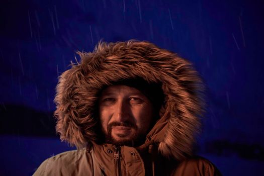 portrait local authentic eskimo  man at winter in stormy weather wearing warm  fur jacket in northern cold night