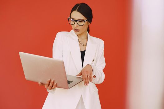 Woman in a studio. Lady with a laptop. Brunette in a white suit.