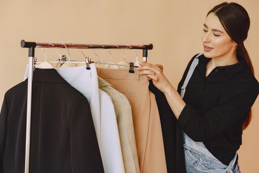 Woman on a brown background. Lady with clothes on a hanger.