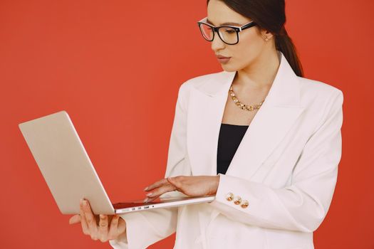 Woman in a studio. Lady with a laptop. Brunette in a white suit.