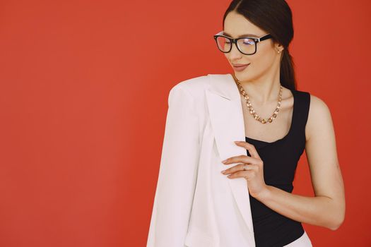 Beautiful girl in a studio. Stylish girl on a red background. Lady in a jacket.