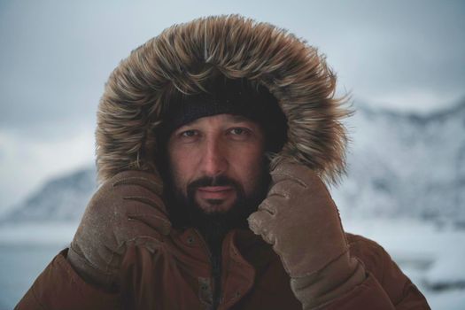 portrait local authentic eskimo  man at winter in stormy weather wearing warm  fur jacket