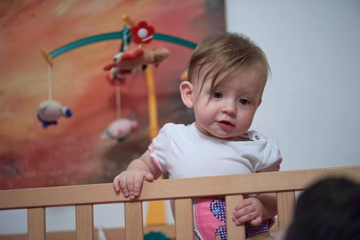 cute  little one year old baby playing with toys in bed while making first steps and learnig to walk