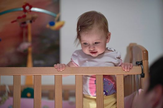 cute  little one year old baby playing with toys in bed while making first steps and learnig to walk