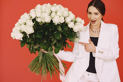 Beautiful girl in a studio. Stylish girl on a brown background. Lady with bouquet of white roses.