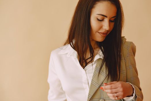 Beautiful girl in a studio. Stylish girl on a brown background. Lady in a jacket.