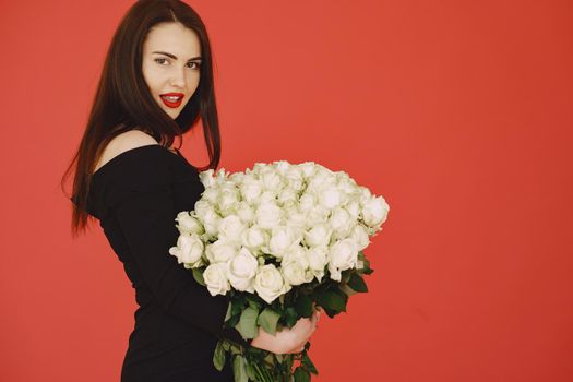 Woman in a studio. Girl with roses. Lady on a red background.
