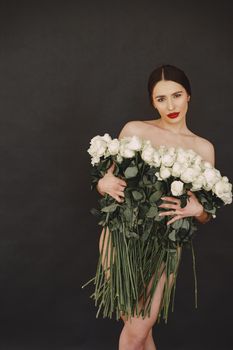 Beautiful girl in a studio. Stylish girl on a black background. Lady with bouquete of roses.