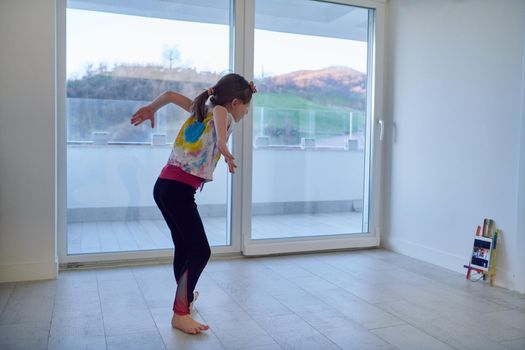 Little girl have online training over  tablet and doing modern ballet dance exercise at home. Online education concept class in modern ballet school. Social distance during quarantine, self-isolation in coronavirus