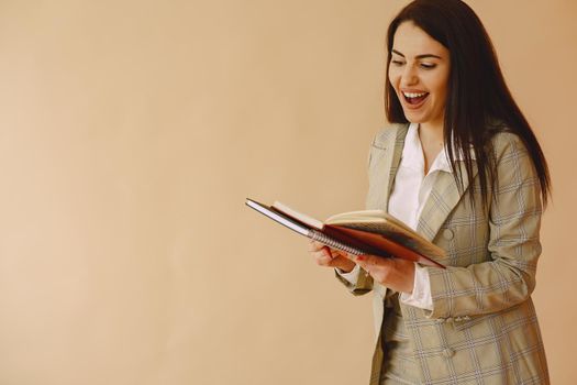 Woman in a studio. Lady with a notebook. Brunette in a brown jacket.