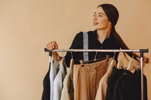 Woman on a brown background. Lady with clothes on a hanger.