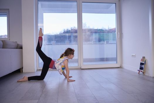 Little girl have online training over  tablet and doing modern ballet dance exercise at home. Online education concept class in modern ballet school. Social distance during quarantine, self-isolation in coronavirus