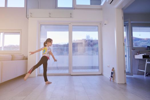 Little girl have online training over  tablet and doing modern ballet dance exercise at home. Online education concept class in modern ballet school. Social distance during quarantine, self-isolation in coronavirus