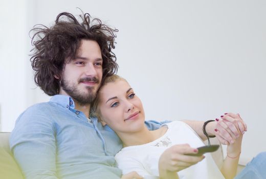 Young couple on the sofa watching television together in their luxury home