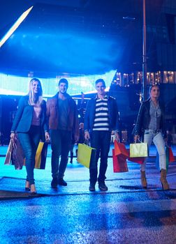 Group Of Friends Enjoying Shopping Trip Together
group of happy young frineds enjoying shopping night and walking on steet on night in with mall in background