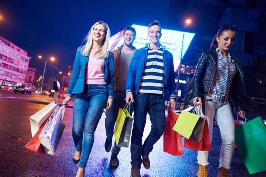 Group Of Friends Enjoying Shopping Trip Together
group of happy young frineds enjoying shopping night and walking on steet on night in with mall in background