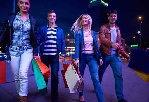 Group Of Friends Enjoying Shopping Trip Together
group of happy young frineds enjoying shopping night and walking on steet on night in with mall in background