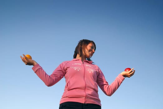young woman balancing fruits in nature (healthy food and low calorie food concept)