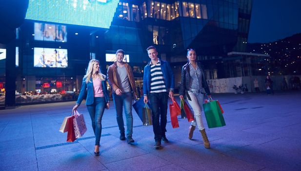 Group Of Friends Enjoying Shopping Trip Together
group of happy young frineds enjoying shopping night and walking on steet on night in with mall in background