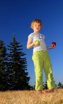 young girl balancing fruits in nature (healthy food and low calorie food concept)