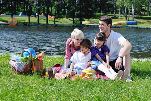 Happy young  family playing together with kids and eat healthy food  in a picnic outdoors