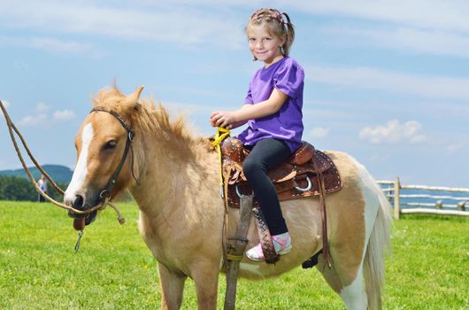 happy child ride farm animal brown pony with blue sky in background and beautiful nature