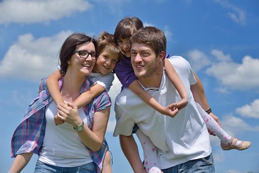 happy young family with their kids have fun and relax outdoors in nature with blue sky in background