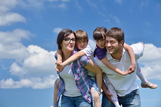 happy young family with their kids have fun and relax outdoors in nature with blue sky in background