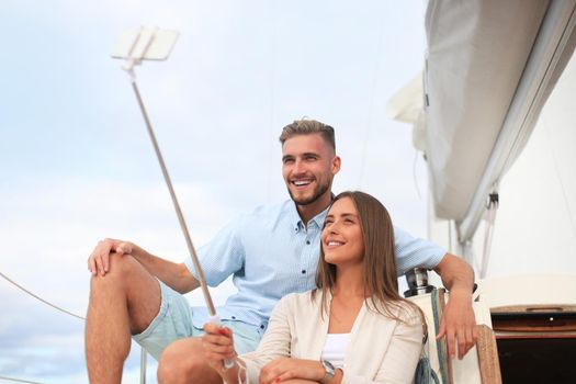 Happy couple taking a selfie after engagement proposal at sailing boat, relaxing on a yacht at the sea.